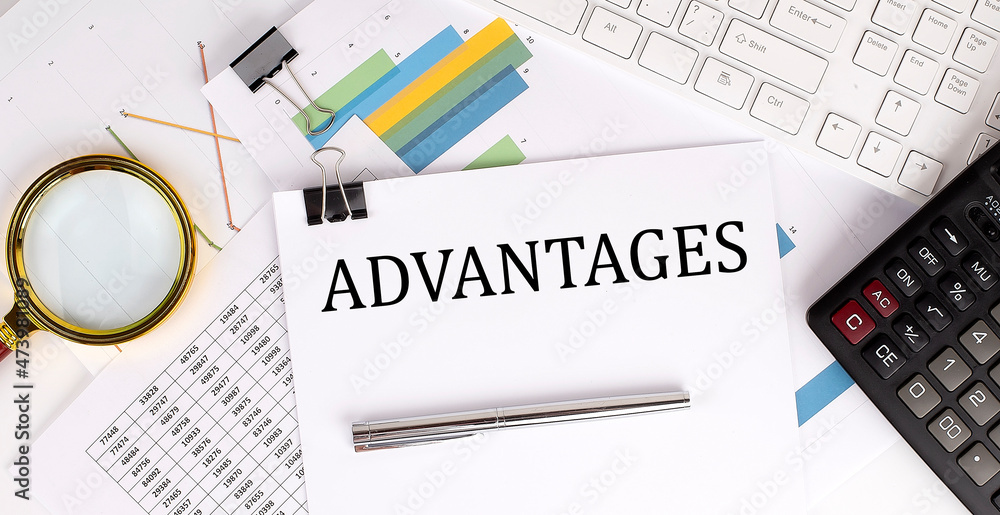 Aufkleber advantages text on the white paper on the light background with charts paper ,keyboard and calculato