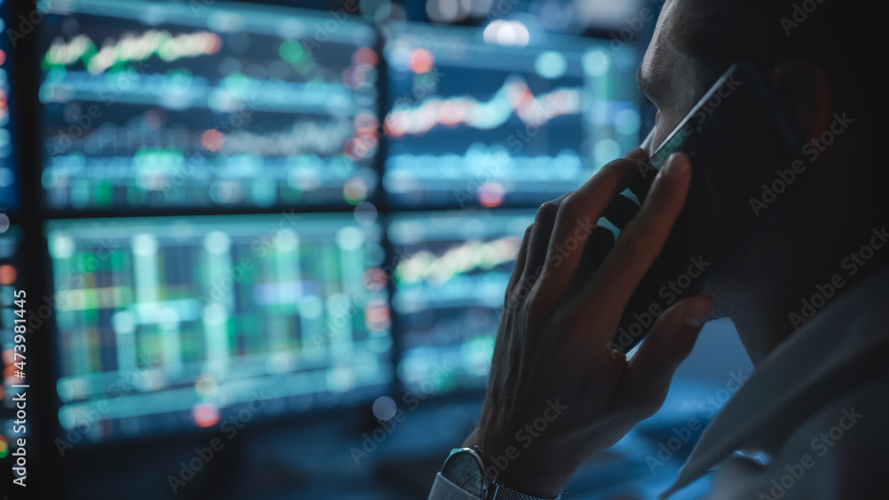 Poster Financial Day Trader Working on a Computer with Multi-Monitor Workstation with Real-Time Stocks Charts and Talking on a Phone with a Client, While in Office Late in the Evening. Close Up Focus.