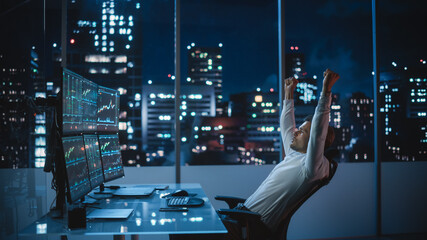 Stock Market Day Trader Working on Computer with Multi-Monitor Workstation with Real-Time Investment, Commodities and Foreign Exchange Charts. Successful Businessman Punches Air for Winning a Trade. - obrazy, fototapety, plakaty