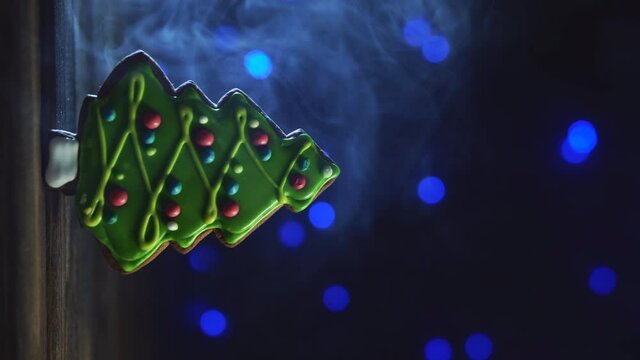 Gingerbread in shape offir-tree, vertical orientation. Christmas concept with copy space. Cookie on blurred background with thick smoke, soft focus.