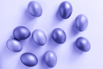 Shining golden eggs on a purple background. Happy Easter. Trendy color of the year 2022.