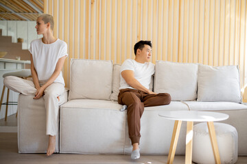 Multiracial couple sitting offended at each other on sofa at home. Concept of family relationship....