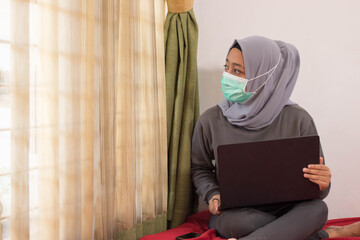 Asian women wearing hijabs wearing masks are working from home