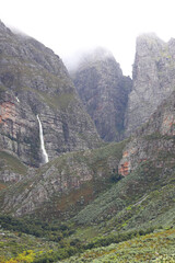Fototapeta na wymiar Waterfalls streaming down the majestic du Toitskloof mountains with rain clouds on the peaks