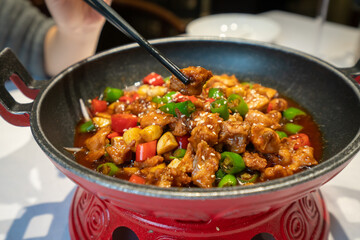 Delicious fried chicken with chili in an iron pot