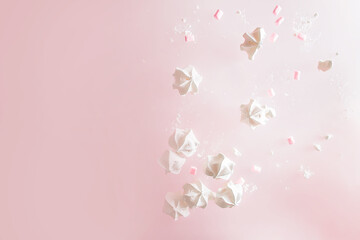 white meringue cookies flying over pink background. Levitation trend photo. Copy space. Sweet baking and cooking concept. High quality photo