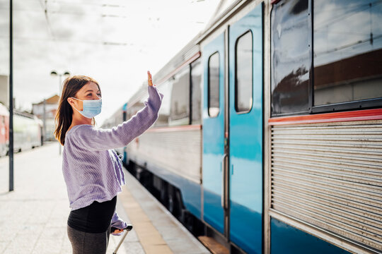 Young woman waving on the platform to somebody leaving by train.