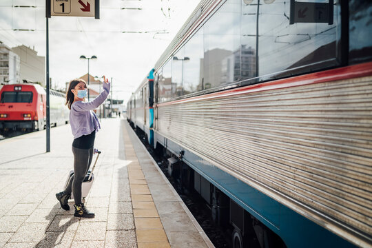 Young woman waving on the platform to somebody leaving by train.