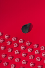 Winter pattern made of black ice cream cone and red christmas baubles with snow flake oranaments on vivid red background copy space. Close up perspective.