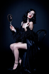 Retro burlesque diva in black corset, posing with a mirror