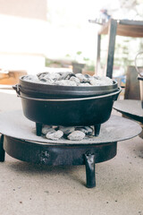dutch oven covered with light gray coals for cooking in it