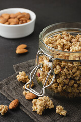 Granola in jar and almonds in white bowl.