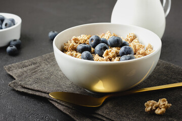 Granola with blueberry in bowl on dark napkin.