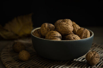 Close-up of walnuts in a grey bowl on a dark background. Dark moody food photography style. Horizontal still life with selective focus and copy space