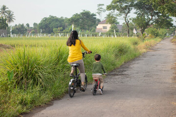 A beautiful mother playing a bicycle with her son