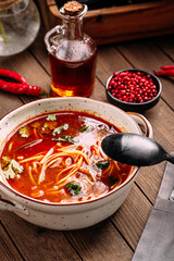 Portion of red hangover noodle soup with parsley