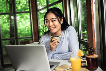 Young Asian woman working using laptop in coffee shop.