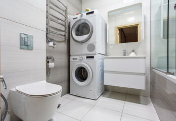 A modern bathroom with Laundry space with washing machine and dryer.