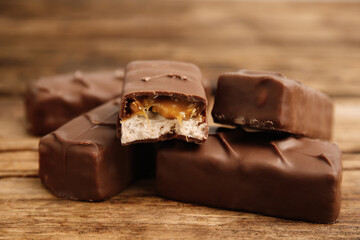 Chocolate bars with caramel, nuts and nougat on wooden table, closeup