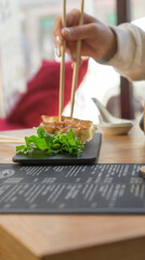 Asian snack in a restaurant, gyoza and chopsticks in hand