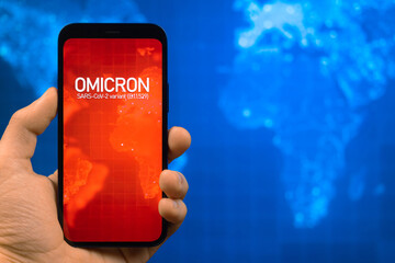 Omicron variant of coronavirus. Mobile phone with omicron text against world map background....