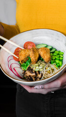 Bowl salad with fried tofu and vegetables in hands
