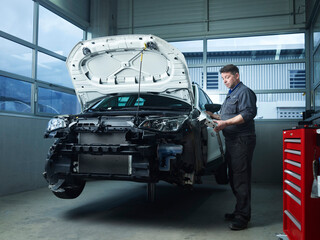 Mature expert installing car parts at auto repair shop