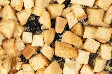 Baked crackers on black background close up. heap small pieces dried bread. crumbs of bread croutons