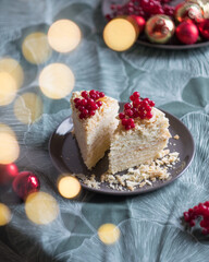 Two pieces of layered cake with cream Napoleon millefeuille vanilla with red berries and blurred new year lights on green background. Selective focus
