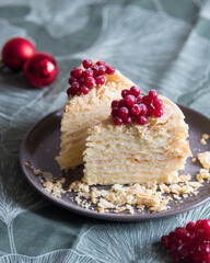 Two pieces of layered cake with cream Napoleon millefeuille vanilla with red berries on green background. Selective focus