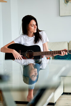 Mid Adult Woman Playing Guitar At Home