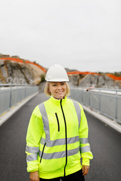 Portrait of female engineer in reflecting clothing standing on bridge