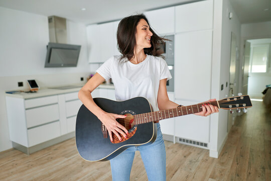 Happy woman playing guitar at home