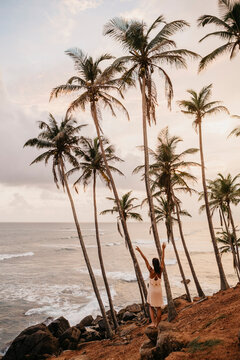 Full length of woman enjoying by palm trees while looking at sea against sky in Sri Lanka