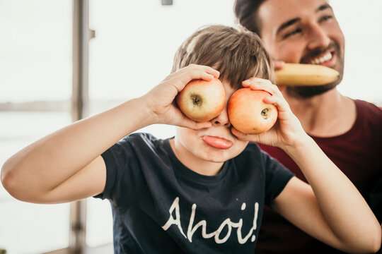 Playful boy covering eyes with apples