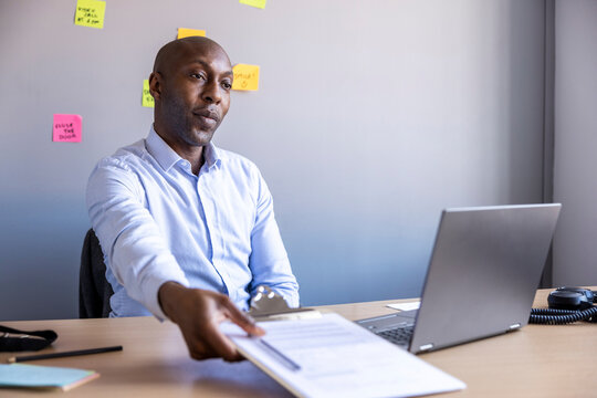 Businessman giving document to client at office