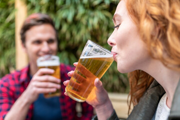 Woman drinking beer in glass at pub