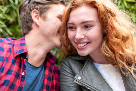 Man whispering girlfriend at pub