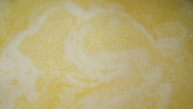Ghee is clarified butter. Boiling yellow butter with small white bubbles.