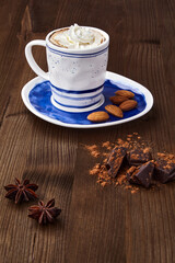 A cup of cappuccino, chopped chocolate, spices and almonds