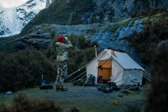 Man in front of tent looking through binoculars