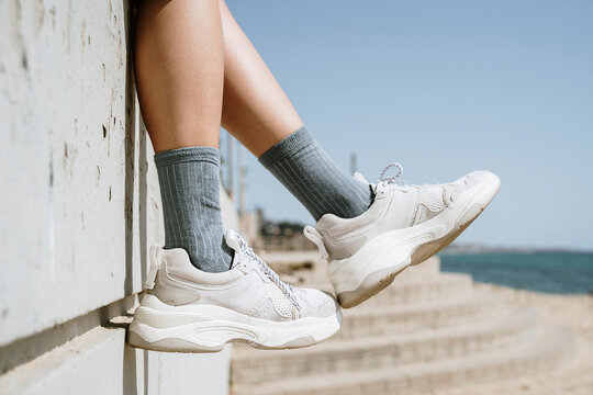 Mid adult woman dangling feet while sitting on retaining wall
