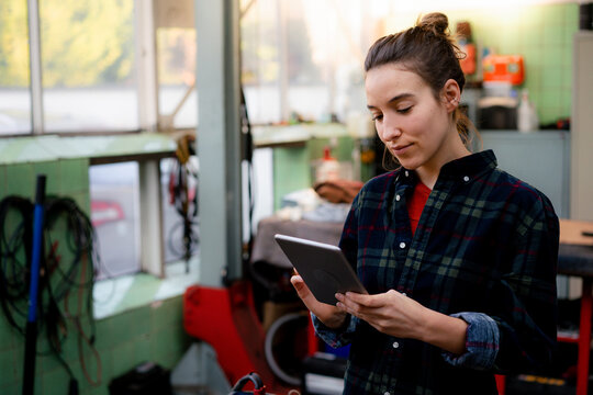 Female mechanic using digital tablet at repair shop