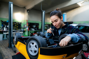 Female mechanic repairing toy car at workshop