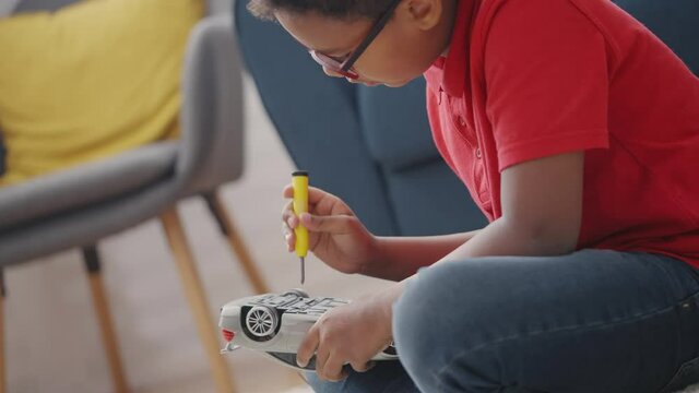 Smart little boy fixing broken toy car with screwdriver, skills development