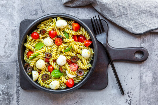 Bowl ofready-to-eatpasta salad with cherry tomatoes, olives, mozzarella cheese and basil - Powered by Adobe