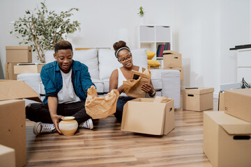 A young couple of college students pack themselves into cardboard boxes, move out of their family homes, go off to college, smile, talk, plan their future - obrazy, fototapety, plakaty