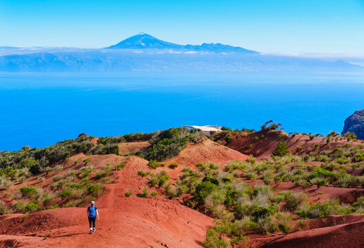Spain, Canary Islands, Agulo, Female backpacker hiking toward Mirador de Abrante observation point with Mount Teide in distant background