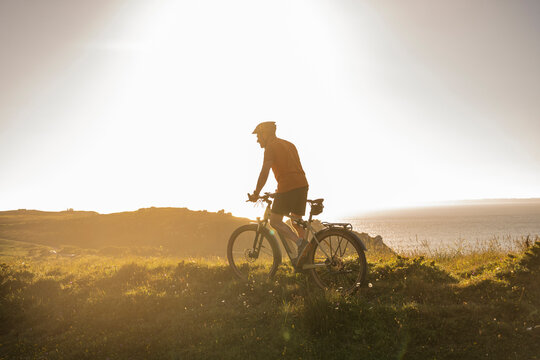 Mature male athlete riding mountain bike at sunset