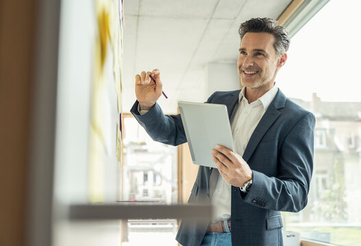 Smiling businessman with digital tablet working at office